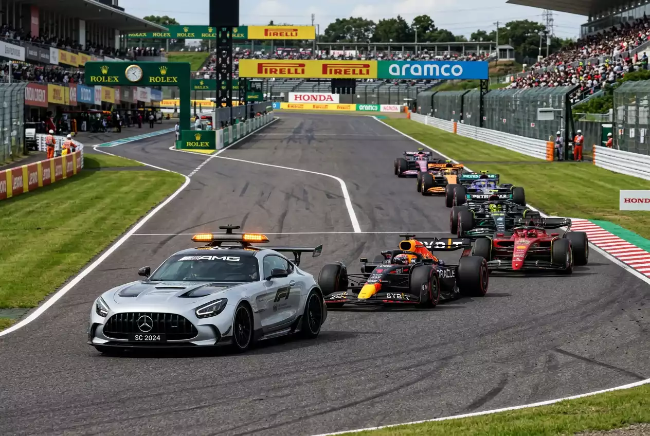 Safety car con luces encendidas liderando un grupo de monoplazas de Fórmula 1